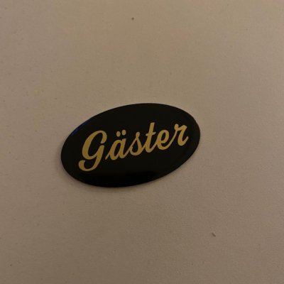Sign Gäster, black/brass 34 x 59mm